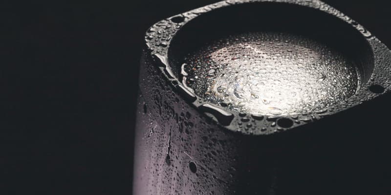Close-up of the Arolla Aqua M-LT front lens beaded with water — its IP66 weatherproof rating in action